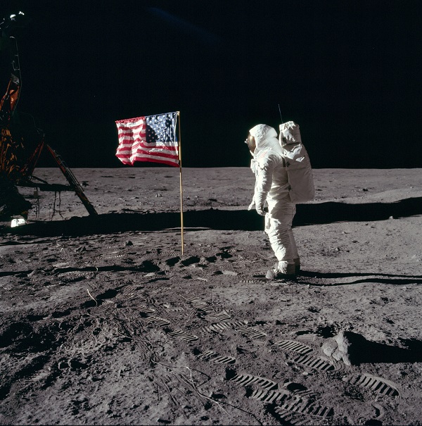 Buzz Aldrin stands with the American flag on the surface of the moon. 